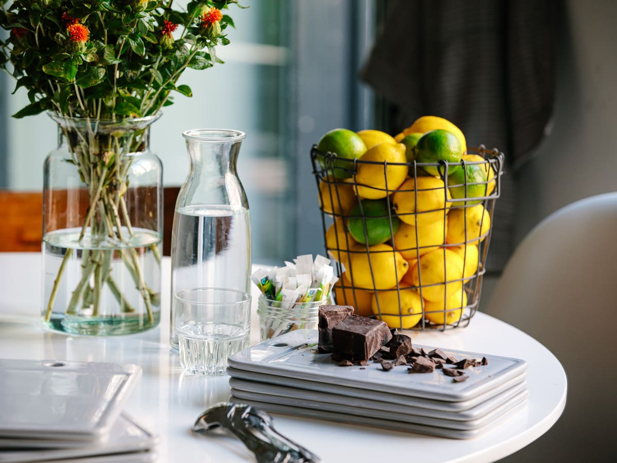 Table set with fresh lemons, dark chocolate and a water carafe by a bright window