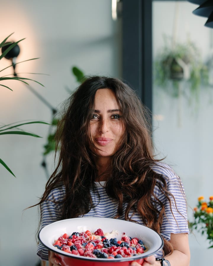 A smiling guest holding a bowl of fresh berries in a bright restaurant dining room